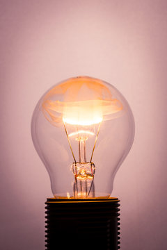 Vintage photo of bulb on light background with flame inside