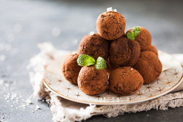 Сhocolate truffles with cocoa powder on white dessert plate