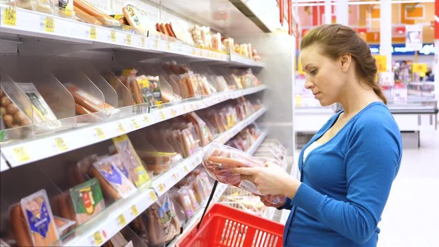 woman buys sausage in supermarket. 4K UHD.