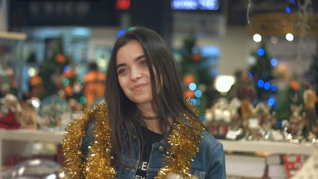 Portrait of a girl in a supermarket.
Slow motion. Young beautiful girl is smiling at the camera. She is in a supermarket, decorated for Christmas.