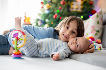 Naklejka premium Six years old preschool boy, playing at home with his newborn baby brother