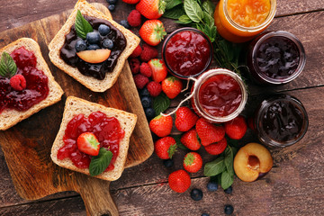 Sandwiches with plum, strawberry jam and fresh fruits on wooden background - obrazy, fototapety, plakaty