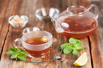 Hot cup of tea with brown sugar and lemon and mint leaves