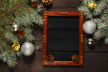 Christmas background with a spruce branch on an old black board and a frame for text. View from above