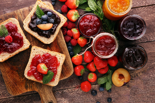 Naklejki Sandwiches with plum, strawberry jam and fresh fruits on wooden background
