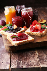 Sandwiches with plum, strawberry jam and fresh fruits on wooden background