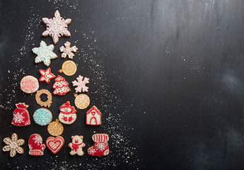 Overhead of Christmas New Year holiday background. Greeting card with gingerbread cookies in shape fir tree on black background. Top view.