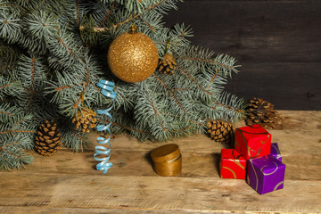 Christmas background decoration with small gifts, and a spruce branch on an old board.