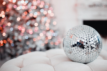 Disco ball. Close-up of a mirror ball against the backdrop of a Christmas tree and garland lights. Concept Christmas, party.