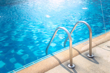 Grab bars ladder in the blue swimming pool