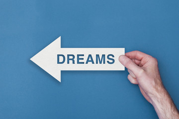 Dreams arrow direction held on a blue background