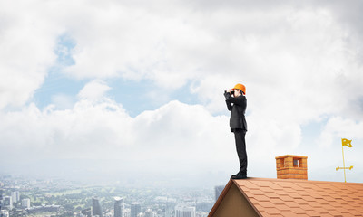 Engineer man standing on roof and looking in binoculars. Mixed media