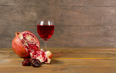 pomegranates, figs, and a glass of wine on a wooden surface
