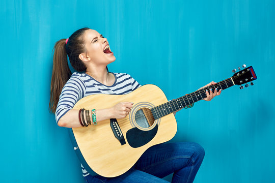Teen girl play on guitar and emotional sings.