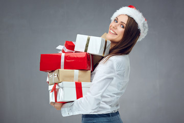Businesswoman wearing Santa hat holding pile of Christmas gift boxes.