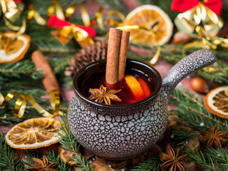 Christmas mulled wine with cinnamon, orange and star anise in a ceramic bowl with winter decorations