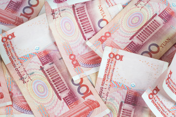 Closeup Chinese yuan bills on table. Yuan is the currency of China, Selective focus on stack of one hundred Chinese yuan banknotes for money background in tone.