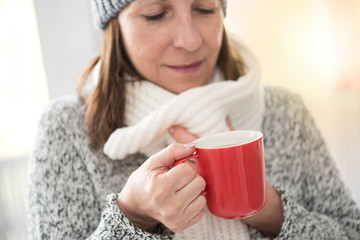 Mature woman drinking hot beverage, light effect