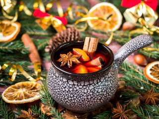 Christmas mulled wine with cinnamon, orange and star anise in a ceramic bowl with winter decorations © Elenglush