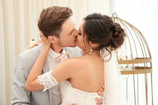 Happy beautiful couple kissing on wedding day, indoors