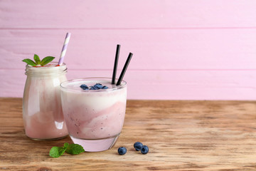 Glassware with different milkshakes on wooden table