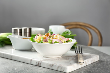 Bowl with delicious potato salad on table