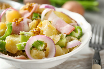 Bowl with delicious potato salad on table, closeup