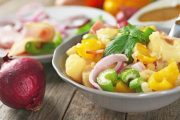 Bowl with delicious potato salad on table, closeup