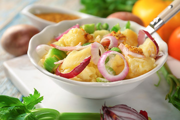 Bowl with delicious potato salad on table, closeup
