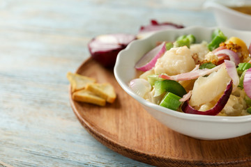 Bowl with delicious potato salad on table, closeup