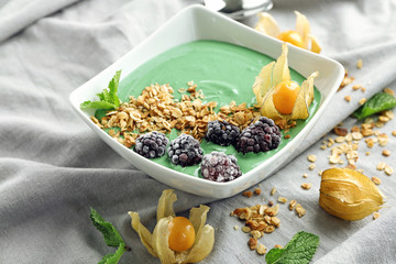 Dish with yummy spirulina smoothie on fabric. Healthy vegan food concept