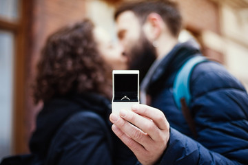 A guy kisses a girl and gives her a diamond ring, a selective focus.