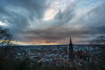 Fototapeta na wymiar Romantic orange sunset above the City of Freiburg in Germany with the ancient church building