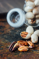 Pecan nuts inside glass jar on rustic surface.