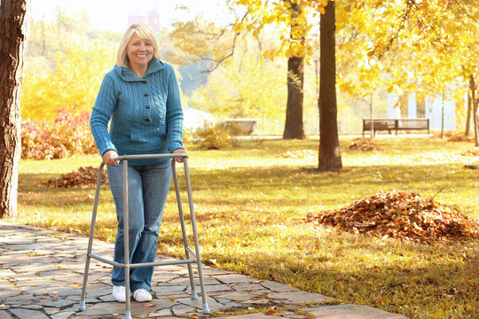 Senior Woman With Walking Frame In Park