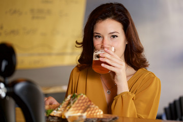 beautiful woman eating roasted sandwich at bar restaurant