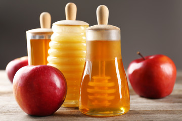 Jars with aromatic honey and apples on wooden table
