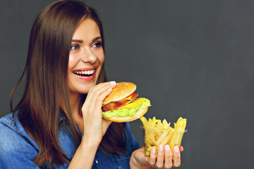 Smiling woman holding burger with potatoes fries
