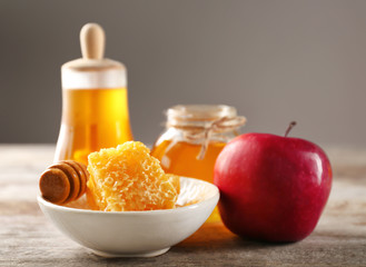 Honeycomb in bowl and apple on wooden table