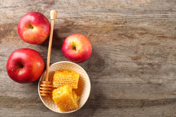 Honeycomb in bowl and apples on wooden table