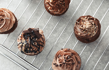 Grid with tasty chocolate cupcakes on table