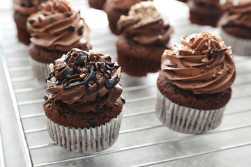 Grid with tasty chocolate cupcakes on table