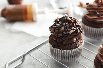 Grid with tasty chocolate cupcake on table