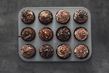 Muffin tin with tasty chocolate cupcakes on grey background