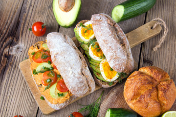 Sandwiches with avocado, eggs and tomato on a wooden background. Fresh organic vegetables, eggs and whole wheat bread. Healthy breakfast. Retro style.