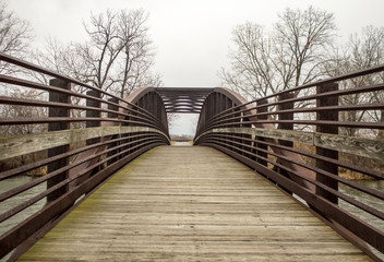 Crossing Over. Wood and metal bridge with diminishing perspective crosses over a stream in Sterling...