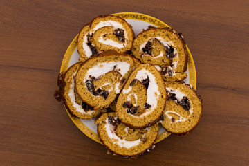 Slices of cake with prunes on a plate on wooden table