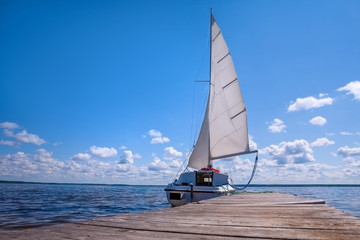 Naklejka premium The yacht is near the pier. Blue sky and water. The concept of recreation and travel.