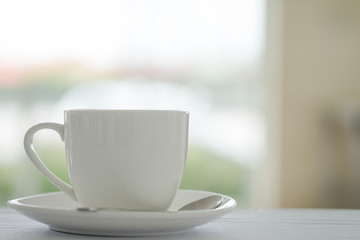 Cup of coffee placed on white table and blurred garden background.