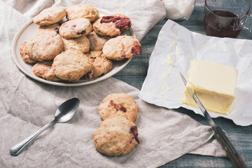 Traditional British dessert, scones with strawberrie. Sweet coconut cookies with raspberry jam and yogurt on wooden table.